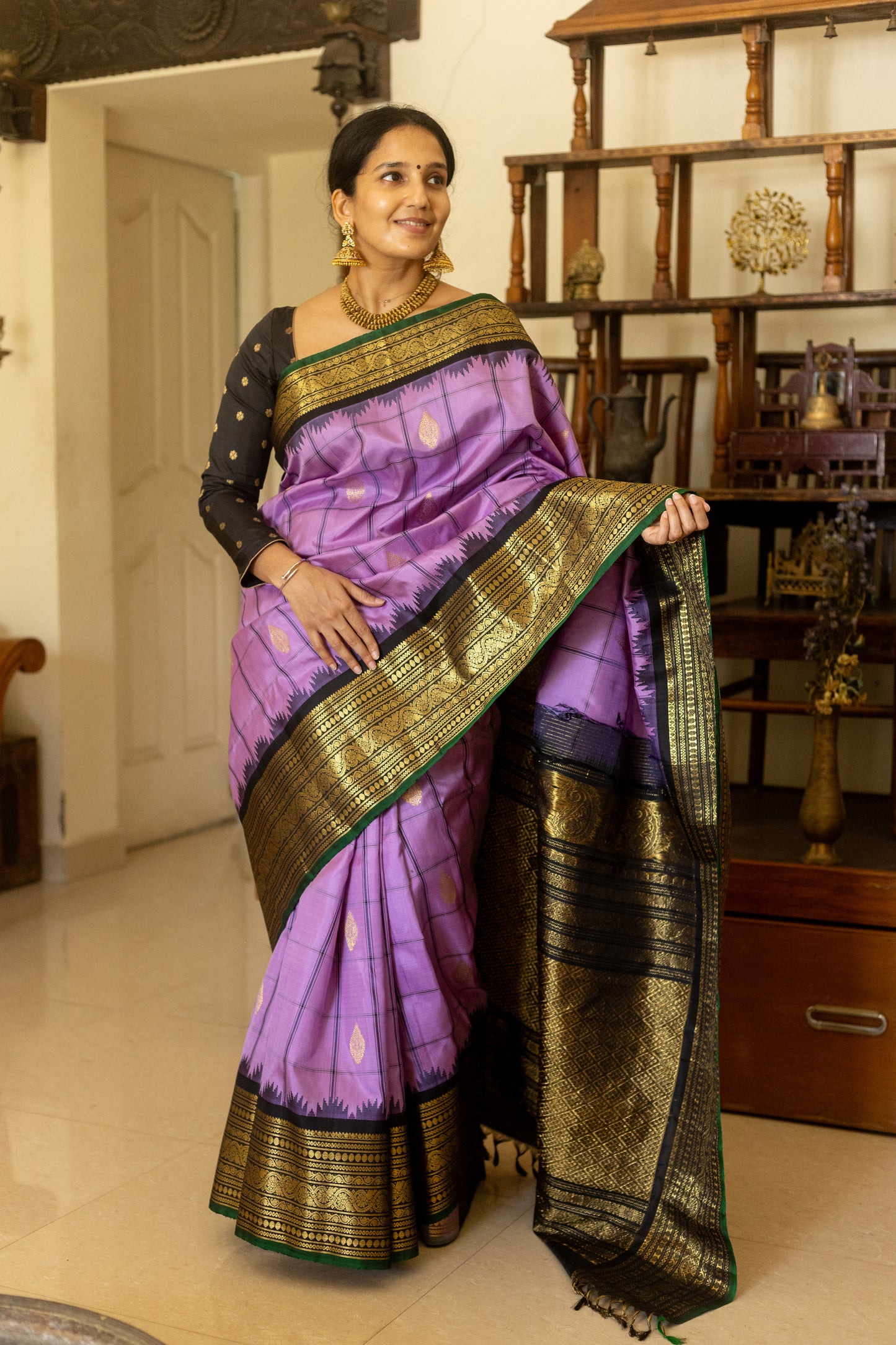 Woman in a purple saree with gold border indoors