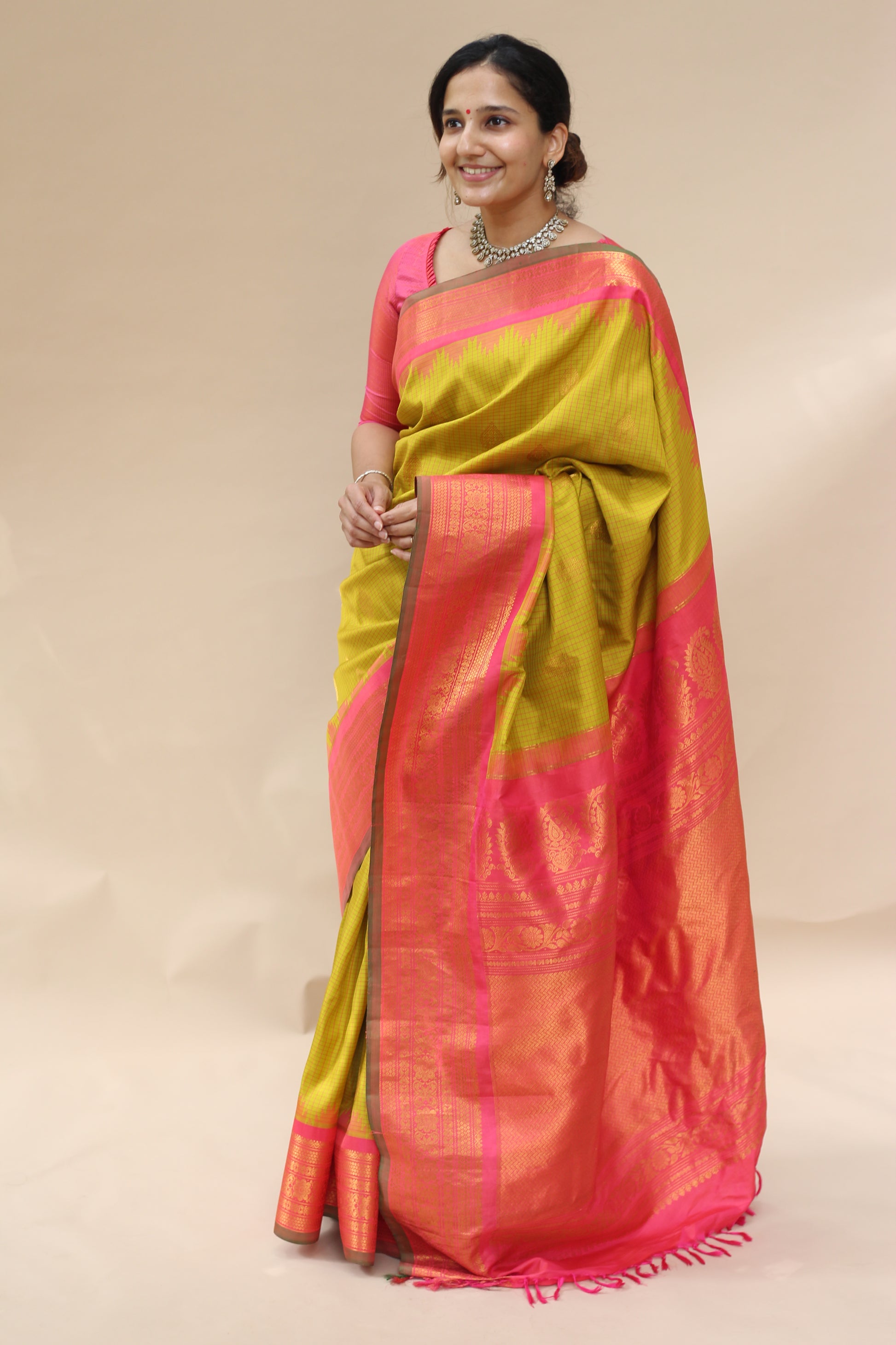 Woman wearing a yellow and pink saree on a plain background